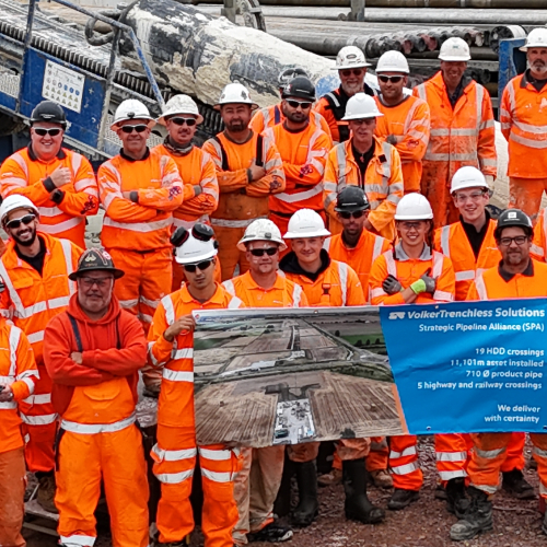 Team photo of people in orange high vis holding a banner.
