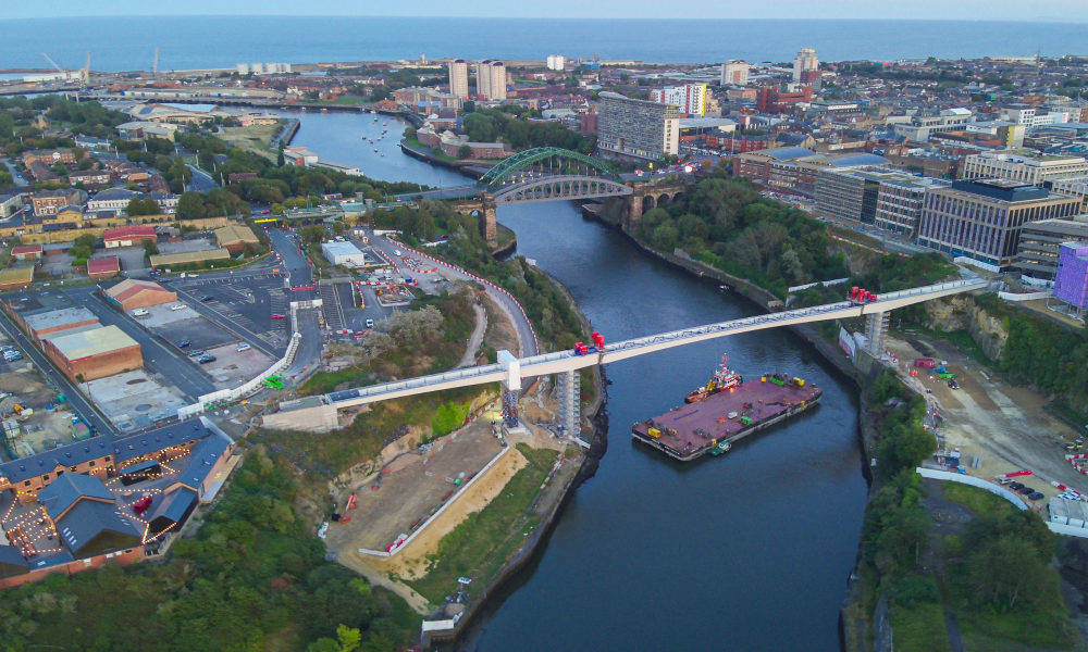 A barge on a river going under a bridge. 