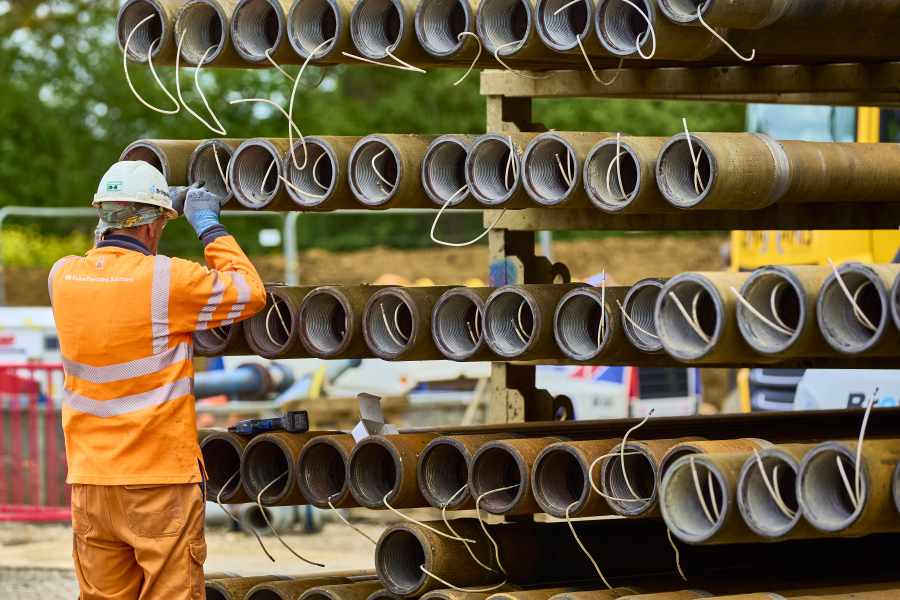 Man in high vis inspecting pipes.