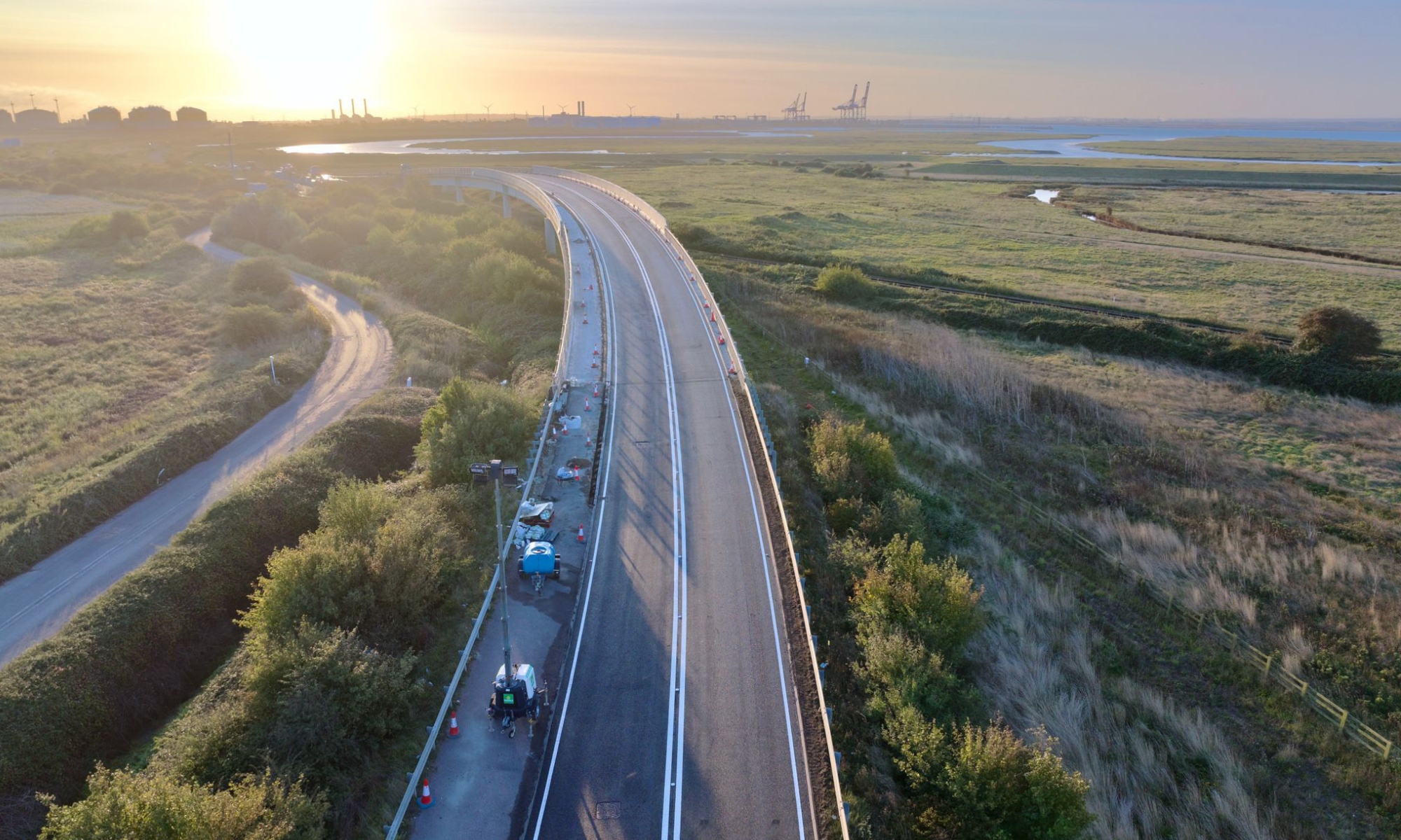 A road at dawn with fields either side 